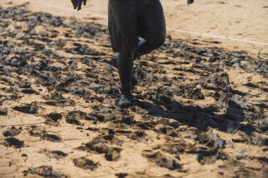 Adam siyah kil ayağa sürülür. Vücut üzerinde siyah kil. Doğa. Kil şifa siyah. Bir kil yüzeye koşan bir adam. Islak kil doğada. Rezervuar.