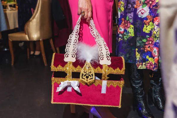 Woman holding a Kazakh national chest of felt. Kazakh national ornaments and decorative embroidery on the material. The event at the restaurant.