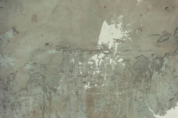 Gray concrete surface. Wall of house. Decorative plaster. White paint on concrete. Worn texture of the paint. Construction of buildings.