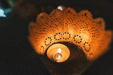 Dekoratif beyaz bir tencerede küçük bir mum. Masada yanan mum. Dekoratif unsur. Beyaz plastik çiçek pot.