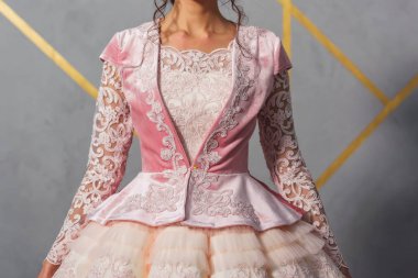 Kazakça Ulusal gelinlik. Dantel kumaş. Kabarık etek elbise. Süslemeler ve kumaşta nakış. Duvar gri. Pembe elbise. Kazakça gelinin geleneksel elbisesi.