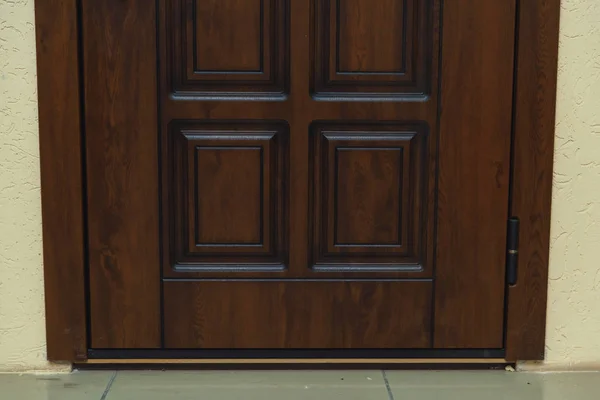 Brown metal entrance door. Metal door as wooden. Door decoration elements.