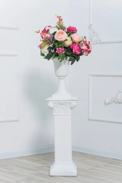 Pembe peonies bir buket. Beyaz vazo çiçekler. Odanın dekoru taze çiçeklerle dekore edilmiştir. Sıva beyaz duvarlar üzerinde çalışıyor. Bahar fotoğraf bölgesi. Sütun üzerinde vazo.