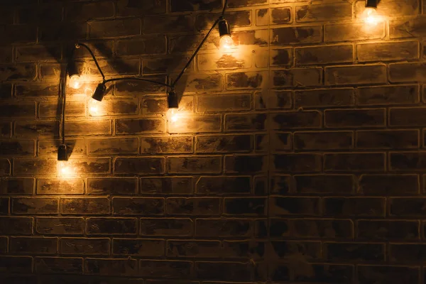 Brick wall texture. The interior of the room. Finishing material. Repair of premises. Brick wall in the interior. Lights on the wire hanging on the wall. The lights in a dark room.