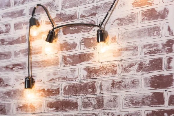 Brick wall texture. The interior of the room. Imitation of masonry. Finishing material. Repair of premises. Brick wall in the interior. Lights on the wire hanging on the wall. Lights on.