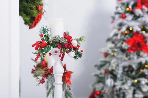 赤と銀の丸いおもちゃ 光る花輪 ポインセチアの花で飾られたクリスマスツリー 白い見掛け倒しの羽 松葉の枝で飾られたキャンドル 壁にクリスマスリース — ストック写真