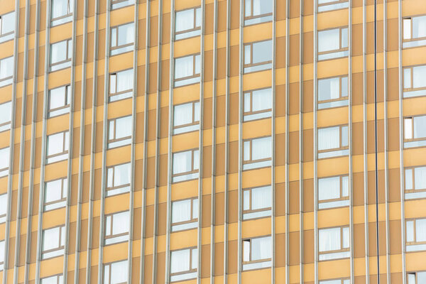 The texture of a multi-storey building. Multi-storey house with apartments. The building is light brown.