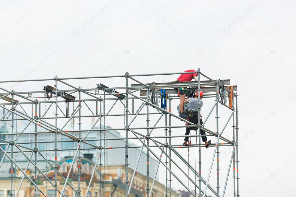 Metal scaffolding. Construction of a storey building. Workers in colorful helmets at the construction site.