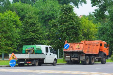 Yol işaretleri yol tamir ediliyor. KAMAZ portakal ağaçları karşı. Yol onarım için araba.