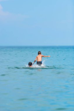 Denizde yüzme oğlu olan bir adam. Kırım'dinlenme. Karadeniz. Bir adam bir çocuk su üzerine atar..