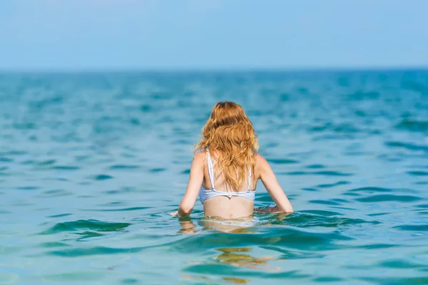 Girl swimming in the sea. Rest in Crimea. Black Sea. Waves on the surface of the sea. Girl with blond wavy hair.
