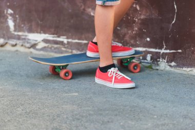 Bir kaykay üzerinde kırmızı spor ayakkabılar içinde biri. Aşırı spor. Şehirde kaykay.