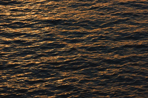 Sunset is reflected on the surface of the water. Black Sea. Waves on the surface of the sea. The texture of the water.