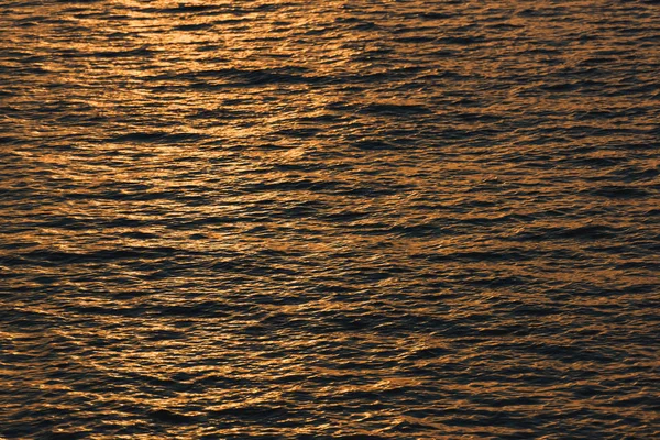 Sunset is reflected on the surface of the water. Black Sea. Waves on the surface of the sea. The texture of the water.