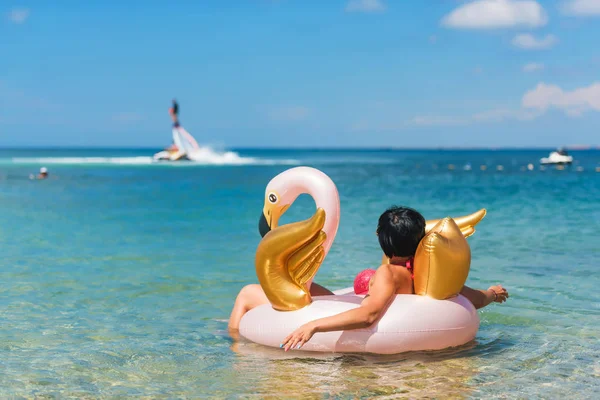 Woman on the inflatable circle of flamingos. A woman swims in the sea on a flamingo. Rest on the Black Sea. The girl in the sea on the background of water attraction.