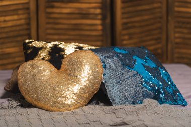 Kalp şeklinde yastık. Ahşap katlanır ekran iç için. Renkli yastıklar pullu yatak ile. Yatağın üzerine ahşap katlanır ekran arka planı.