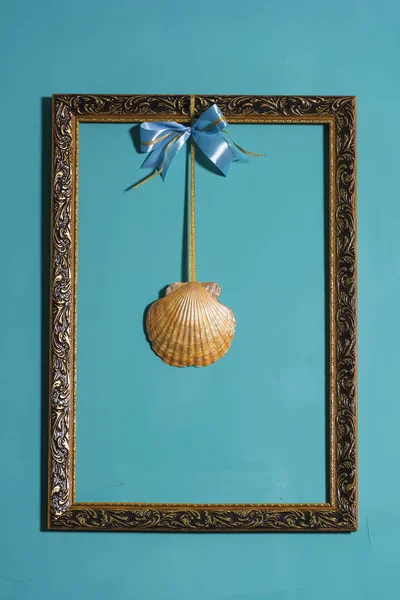 Decoration of the room in the marine style. Gold frames on blue wall background. Decorative element. Vintage gold-plated frame with seashells. Vintage photo zone.
