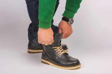 Ayakkabıları deniyorum. Erkek botları bacaklarda. Beyaz arka planda dantel olan ayakkabılar