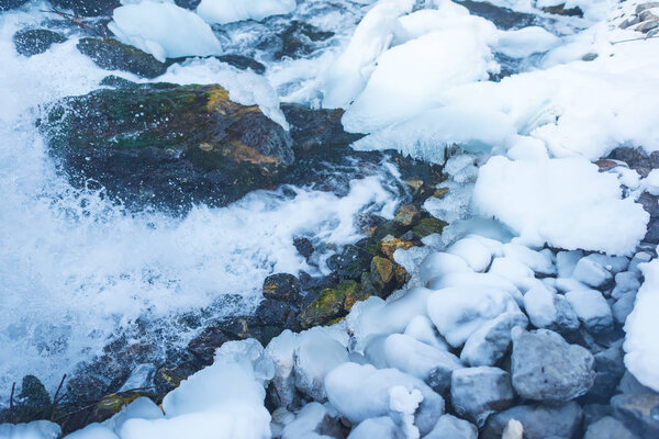 Frozen water channel. Mountain river in winter. Icing on the bank of the stream. Bypass channel. Head of river water from the pipe.