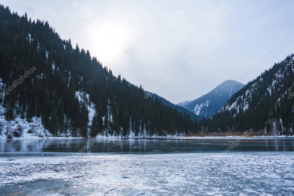 Mountain lake in winter. Ice-covered lake in the mountains. Lake Kolsay in Kazakhstan.