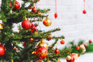 Noel ağacı. Beyaz tuğla duvar. Dekoratif şömine. Kırmızı kurdeleler üzerinde Noel oyuncakları. Çam dalları çelenk. Dolu hediyeler. Kırmızı ve altın topları.