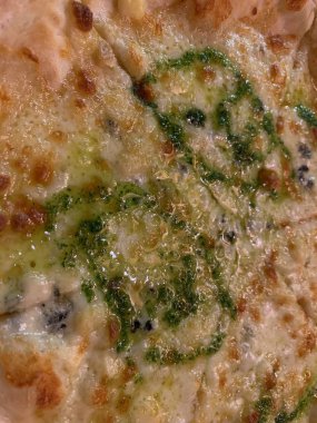 Peynir pizzası. Pizza yüzeyinde yeşil pesto sosu. Eritilmiş peynir dokusu. Pizza 4 peynir.