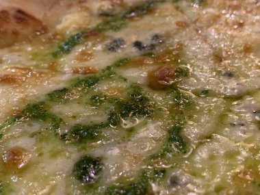 Peynir pizzası. Pizza yüzeyinde yeşil pesto sosu. Eritilmiş peynir dokusu. Pizza 4 peynir.