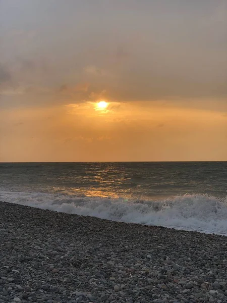 Sunset in a cloudy sky on the sea. Big wave. Rest on black sea. Rocky beach of Batumi.