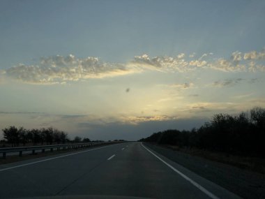 Yol gezisi. Ülke parkuru. Bulutlu gökyüzüne karşı yol. Akşam yolda Binicilik.