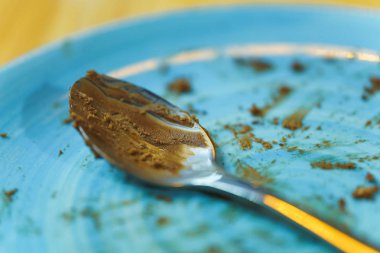 Kirli mavi tabak. Tatlının altındaki yemekler. Çikolatalı pastadan sonra kirli tabak ve kaşık. Yemeklerde çikolata parçacıkları.