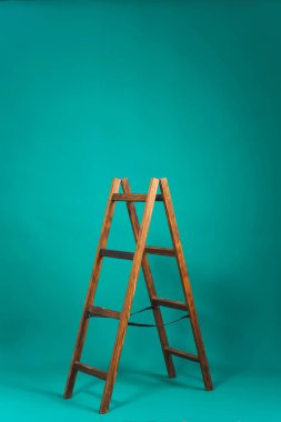 Koyu yeşil arka planda ahşap merdiven. Dekor ile stüdyo Kağıt arka plan. Bir fotoğraf stüdyosunda profesyonel Kağıt arka planda ahşap kahverengi merdiven.