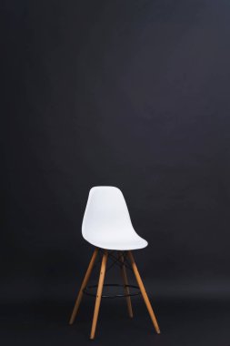 Siyah arka planda beyaz sandalye. Stüdyo Kağıt arka plan. Plastik arka ve ahşap bacaklar ile tasarım Bar dışkı.