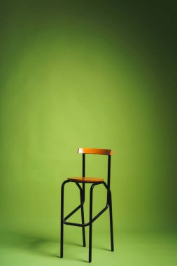 Açık yeşil arka planda Bar dışkı. Dekor ile stüdyo Kağıt arka plan. Metal bacaklarla ahşap mama sandalyesi.