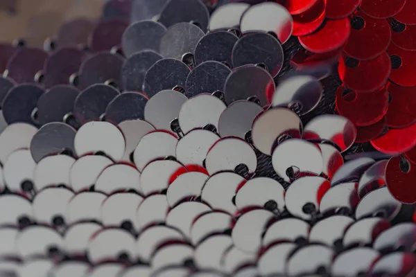 Bilateral payetler dokusu. Kırmızı ve gümüş çift taraflı payetler. Ölçeklerle kumaş. Dikiş için payetler ile malzeme.