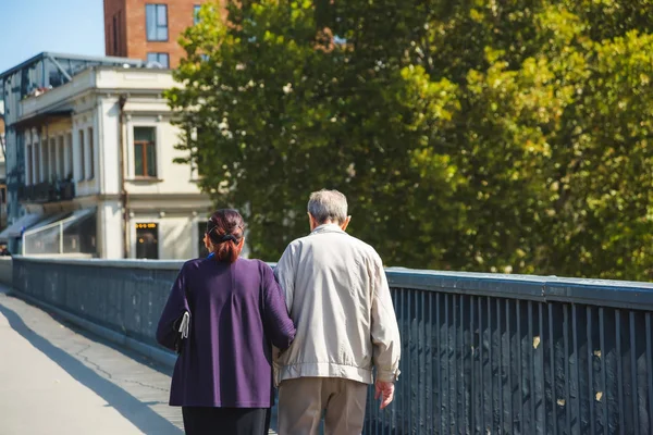 Old man and woman walking on the bridge in Tbilisi. Rest in Georgia. Large bridge. Walk around town.