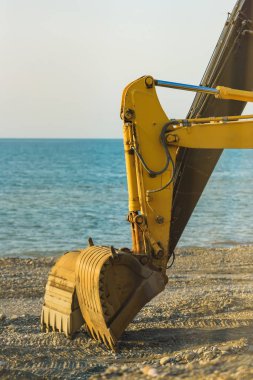 Siyah deniz üzerinde sarı traktör kazma. Batum 'daki gezinti yolu boyunca yürüyebilirsiniz. Denizin yakınında inşaat işleri. Gürcistan 'da dinlenme.