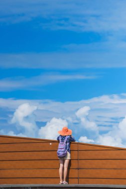 Şapkanın içindeki kız Batum 'daki gözlem güvertesinde. Bulutlu gökyüzü arka planda ahşap çit. Gürcistan 'da dinlenme.