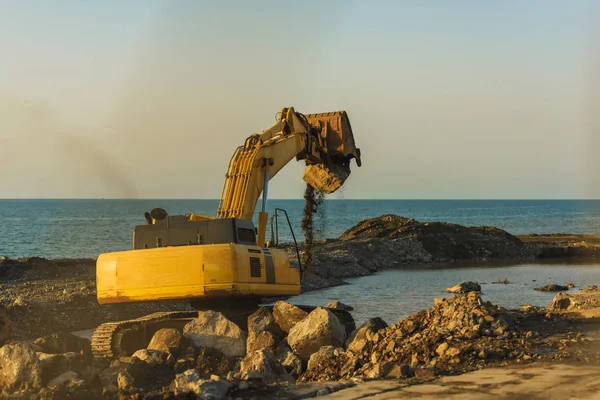 Yellow tractor digging on the black sea. Walk along the promenade in Batumi. Construction work near the sea. Rest in Georgia.