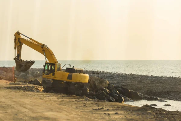 Yellow tractor digging on the black sea. Walk along the promenade in Batumi. Construction work near the sea. Rest in Georgia.