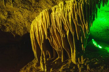 Prometheus Cave in Georgia. Multicolored lighting stalactite cave. Color lighting of stalactites in the cave. clipart