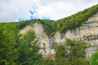 Okatse nehrinin kanyonunda Kinchkha Şelalesi. Georgia 'da dinlenin. Imereti bölgesinde yüksek şelale. Yeşil ağaçlar ile dağın kayalık çıkıntıları.