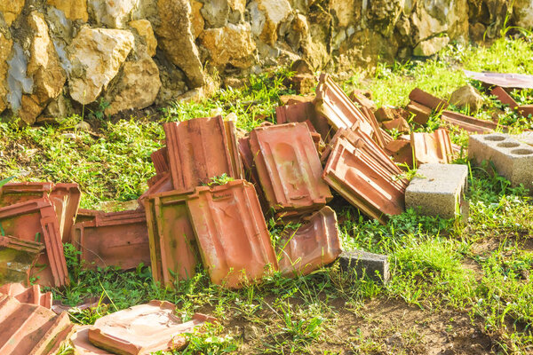 Clay tiles are red in colour. Environmental building material. Clay tiles lying on the green grass.