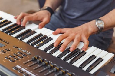 Adam synthesizer çalıyor. Müzik aletinin siyah beyaz tuşları. Elinde gümüş erkek saati var. Piyano çalmak.