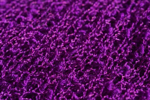 Texture of knitted dark purple fabric. Violet knitted abstract background. Lilac cloth closeup.