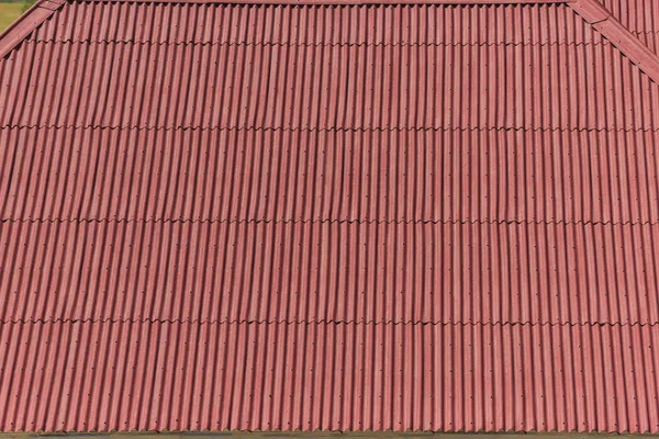 Red metal corrugated roof of the house. Rest in Kyrgyzstan. Big house near lake Issyk Kul. The texture of the iron roof.