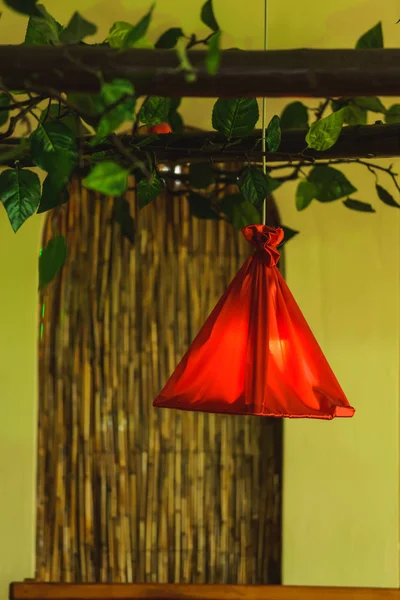 部屋の装飾的な人工植物 天井からひもの赤いバッグが掛かっている 材料の小さな袋 — ストック写真