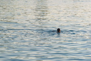 Adam Issyk Kul gölünde yüzüyor. Su yüzeyinin dokusu. Kırgızistan'da dinlenme.