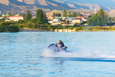 Adam Issyk Kul gölünde bir jet ski üzerinde yüzüyor. Aşırı dinlenme. Su taşıma. Kırgızistan'da dinlenme.