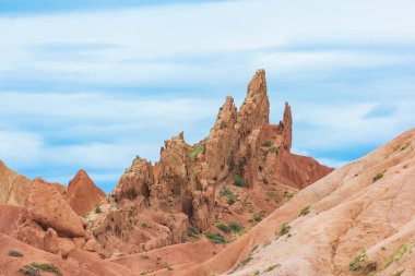 Kırgızistan'da Kanyon Masalı. Kumlu kırmızı oluşumlar. Kanyonun tepelik alanı. Issyk-Kul Gölü bölgesinde doğa.