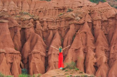 Kırgızistan'da Kanyon Masalı. Kum tepelere karşı kırmızı elbiseli bir kız. Issyk-Kul Gölü bölgesinde doğa.